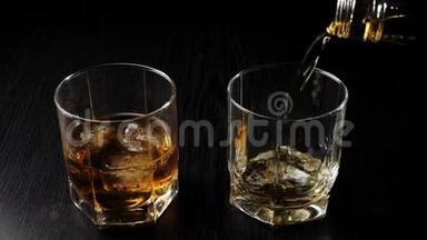 豪华威士忌。 手把金色的威士忌从一个方形的瓶子里倒入一个<strong>玻璃杯</strong>，放在靠近<strong>玻璃杯</strong>的黑桌上，里面有威士忌和冰。